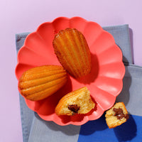 Thumbnail for Three Choco-Hazelnute Madeleines on a plate viewed from above, one has been opened to show the filling inside