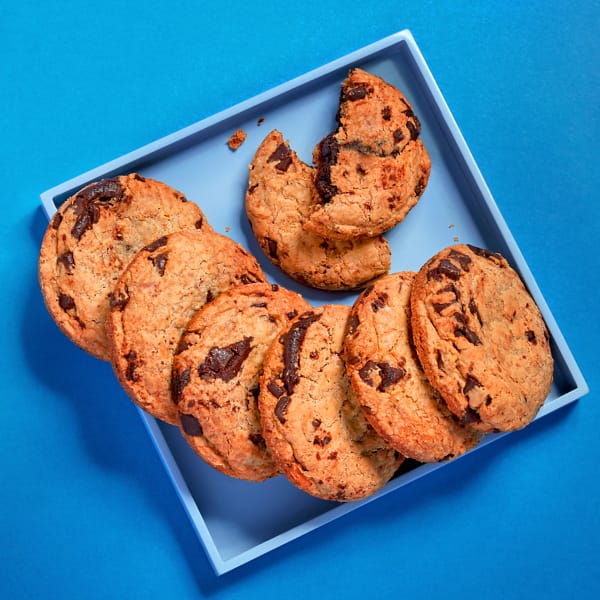 Loaded Chocolate Chip Cookies stacked on a blue surface.