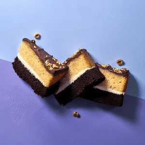 Three slices of layered praline round cake overlapping on a blue and purple contrasting background