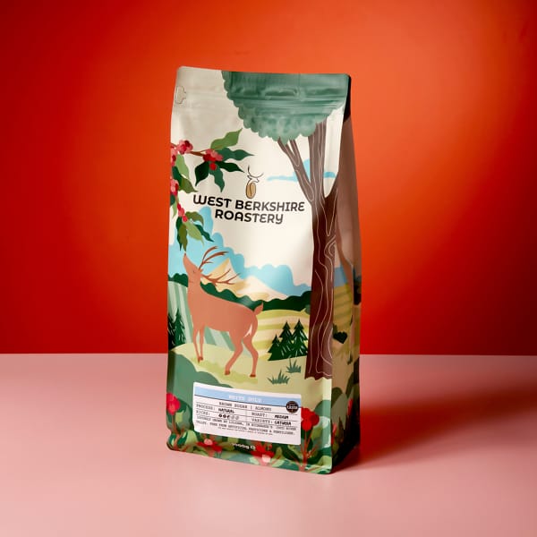 A 1kg bag of West Berkshire Roastery White Gold coffee beans on a peach and orange contrasting background