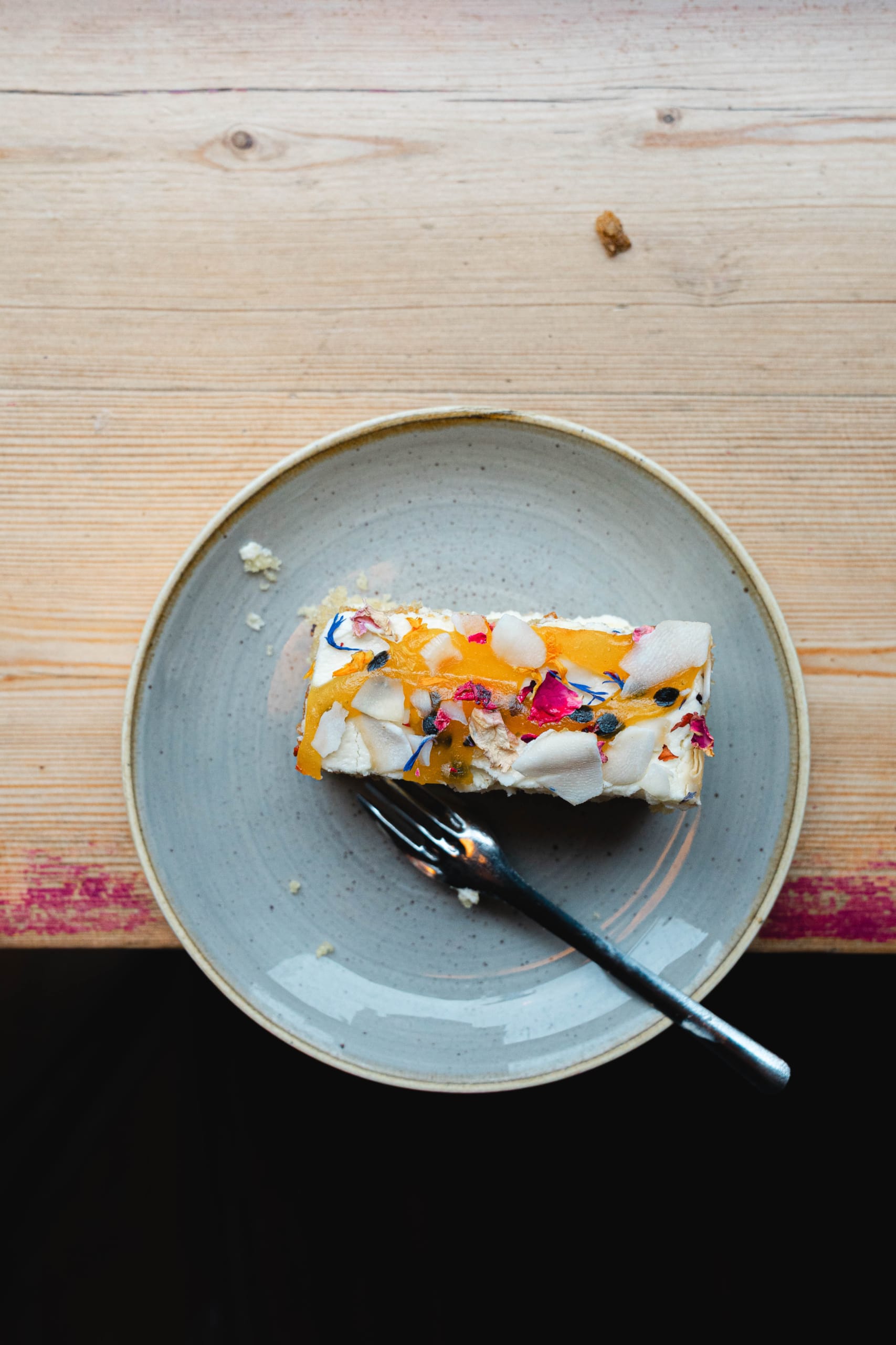 Overhead shot of the Passionfruit and Coconut Traybake from Cake Club on a light blue plate on a side counter.